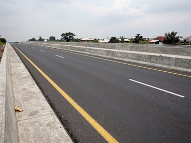 Wide panoramic shot of completed urban road infrastructure in Mexico City, concrete and asphalt surface with lane markings, overcast daylight, no people, documentary infrastructure photography