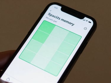 Close-up of an Android phone screen showing a spatial memory grid game with a moves-per-session counter, clean UI, studio-lit, hand visible at bottom edge holding the device