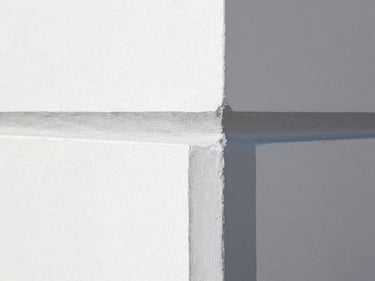 Close-up of a perfectly painted interior wall corner, showing crisp, straight lines where two colors meet, natural coastal daylight.