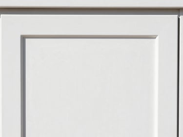Close-up of a newly refinished cabinet door, showing a flawless, glossy white surface with no brush strokes, under bright light.