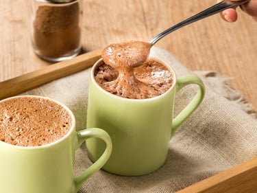 Leite em pó desnatado com whey protein em uma colher sobre fundo claro