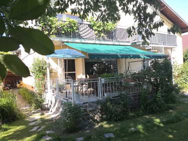 Blick vom Garten auf deine Terrasse mit Sonnenschutz