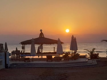 Soft sunrise view over the beachfront swimming pool and traditional arisha at Bedouin Star camp