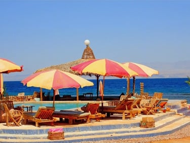 Fresh water swimming pool with colorful red and yellow open umbrellas and a beach Arisha in Egypt