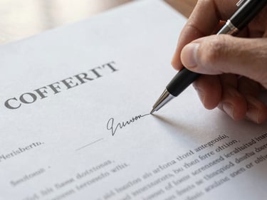 Close-up of a hand holding a pen above a formal contract page, fingertip resting near a signature line, warm natural window light, clean white paper surface, no faces