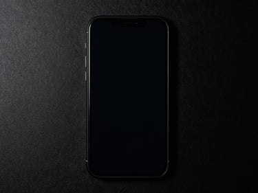 Overhead straight-down shot of a phone on black seamless, screen lit by side strobe, film layer visible with zero impact marks, forensic clarity, no lifestyle elements
