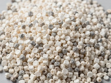 Close-up overhead of HDPE resin granules in natural white and grey tones on a flat industrial surface under studio strobe, granule size uniformity visible, no decorative elements