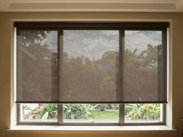 A premium sunlit balcony with durable external roller blinds rolled down, creating a cool shaded sanctuary.