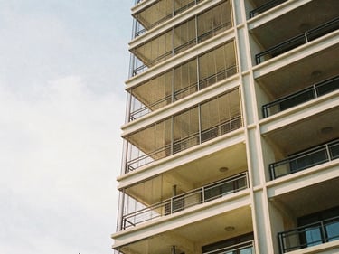 High-tensile invisible grills blending into the bright sky on a high-rise residential balcony, 35mm