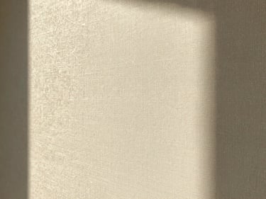 Close-up of textured champagne-toned designer wallpaper catching warm side light, rich paper fibers, 35mm