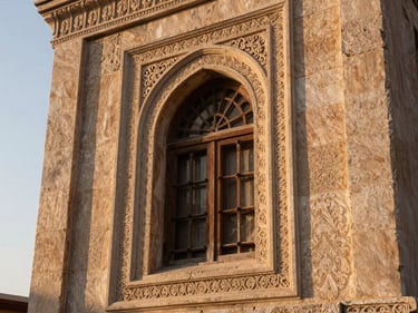 Close-up of an ornate Mardin stone konak window with carved limestone surround, soft morning light from the left, warm ochre tones, no people