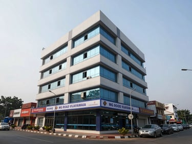 Exterior facade of a four-storey commercial office building on MG Road Vijayawada, overcast morning light, ground-floor glass frontage with signage band, street-level context showing adjacent commercial strip, wide environmental framing