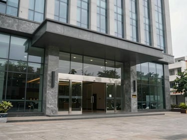 Ground-floor exterior of a modern office building entrance in Benz Circle Vijayawada, overcast daylight, glass doors and polished stone facade visible, empty pavement in foreground