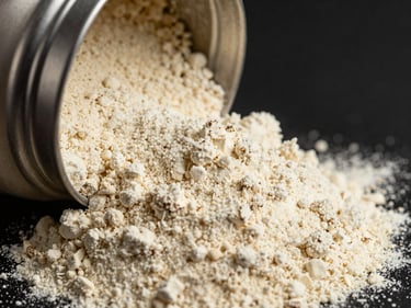 Macro shot of fine creamy protein powder, soft highlights, stainless steel industrial container edge, dark background