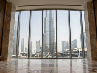 Wide-angle interior entry corridor of a Downtown Dubai penthouse, polished marble floors, floor-to-ceiling glazing, Burj Khalifa visible in mid-distance, natural daylight