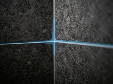 Sleek finished luxury bathroom wet area under construction, blue liquid membrane applied to joints, sharp focus.
