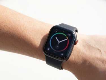 Close-up of a black smartwatch displaying fitness data on a wrist, clean white background, bright high-key product photography, crisp natural daylight, vivid colors, sharp focus, 35mm