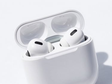 Close-up of sleek white wireless earbuds in their charging case on a clean white surface, bright high-key product photography, crisp natural daylight, vivid colors, sharp focus, 35mm