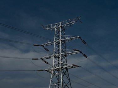 Complex power transmission lines against a dramatic sky, industrial scale, cinematic, premium editorial photography, deep navy and steel tones, architectural framing, 35mm
