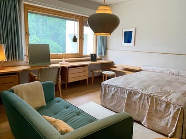 Warm bedroom and sitting area with wooden furniture, large window and natural light