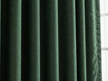 Macro close-up of heavy hunter green curtain fabric texture with deep folds and dramatic side lighting, 35mm