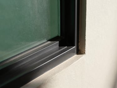 Architectural detail of a matte black pleated grill installed in a window frame, sharp focus, geometric shadows, 35mm