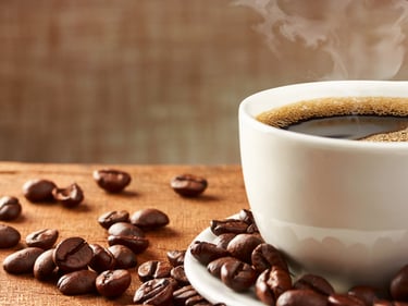 a cup of coffee and some beans on a table