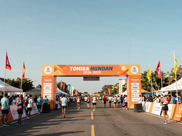Large-scale outdoor marathon finish line, towering custom archway, flags blowing in the wind, bright clear daylight
