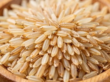 Close-up of golden Basmati rice grains in a wooden bowl, bright natural daylight, rich organic tones, high detail, 35mm