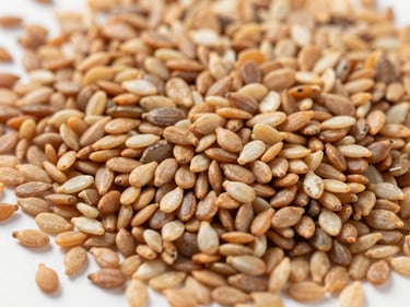 Macro shot of assorted oil seeds (sesame, groundnuts) spread on a clean white surface, bright natural daylight, rich organic tones, high detail, 35mm