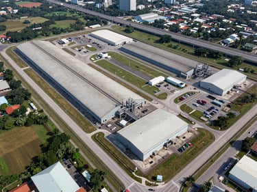 Aerial diagonal view of a large industrial land parcel near Iskandar Malaysia zone, boundary clearly delineated, highway visible in background, daylight