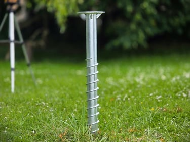 Durable galvanized steel ground screw anchor for secure garden installations in a green lawn.