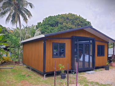 Chalet modulaire moderne avec bardage bois et portes vitrées dans un décor tropical.