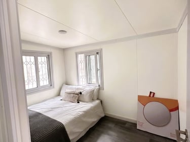 Modern small bedroom with a white bed, dark wood floors, and minimalist white walls.