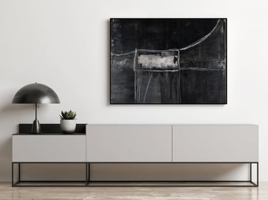 Black abstract wall art hanging above a modern white sideboard with a minimalist metal lamp.