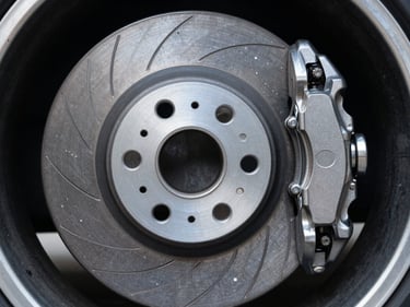 Close-up of a metallic disc brake rotor and caliper on a premium wheel, high contrast studio lighting