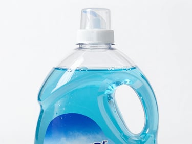 A clear plastic bottle of liquid dishwasher detergent showing high-viscosity blue gel, white background.