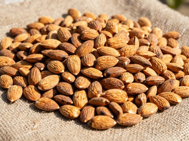 Close-up of freshly harvested almonds in their shells, scattered on a burlap sack, bright natural sunlight.