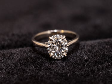 Macro shot of an antique diamond ring resting on dark velvet, soft golden highlights, shallow depth of field.