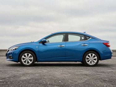 Full side view of a blue Nissan Sentra on a flat grey studio surface, natural overcast light, showing clean bodywork and factory wheels