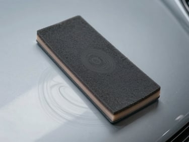 Overhead close-up of polishing pad on car paint surface under studio light, swirl marks visible before correction, controlled environment, neutral gray background