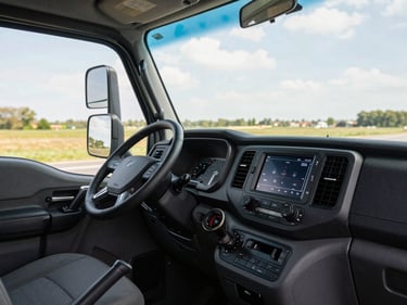 Truck cab interior viewed from the driver seat, dashboard controls in focus, natural daylight through windshield