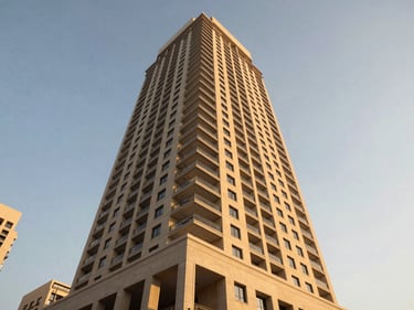 Environmental exterior shot of a mid-rise residential tower in Business Bay at golden hour, shot from street level looking upward, warm facade light against a clear sky, no people, architectural detail visible on the podium level