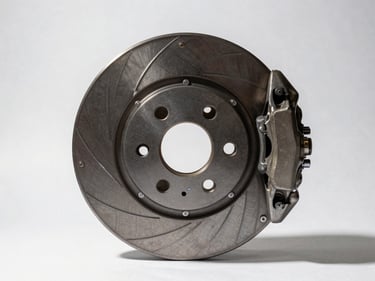 Studio overhead of brake disc and caliper assembly on white surface, part number etched on rotor visible, strong directional shadow