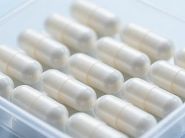 Close-up of clear pharmaceutical capsules in a sterile tray, bright high-key laboratory lighting, sharp macro focus, 35mm