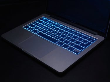 Ultra-thin laptop on a dark surface, glowing blue keyboard, electric blue rim-lighting, dark premium product photography, 8k