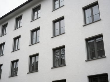 Exterior of a mid-rise residential building showing freshly painted facade surface and window seals, overcast natural light, no people, clean architectural framing from street level