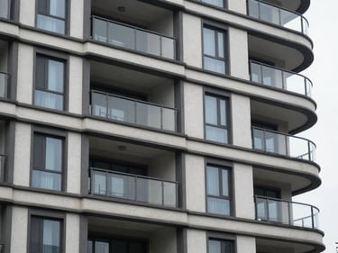 Close-up of a residential condominium building exterior facade showing rendered finish and window framing detail, overcast natural daylight, no people, flat environmental framing