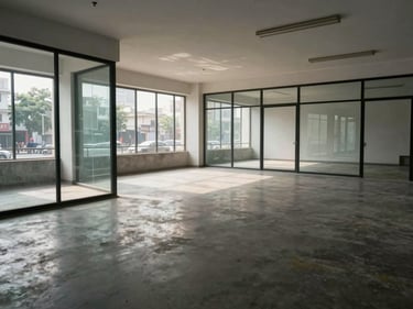 Empty commercial office floor with glass partitions and polished concrete, daylight-balanced north-facing light, Vadodara street view through windows, no people