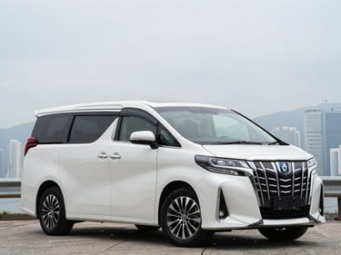 Front three-quarter driver-side profile of a white Toyota Alphard, overcast Hong Kong daylight, full vehicle visible, squared frame, no tilt